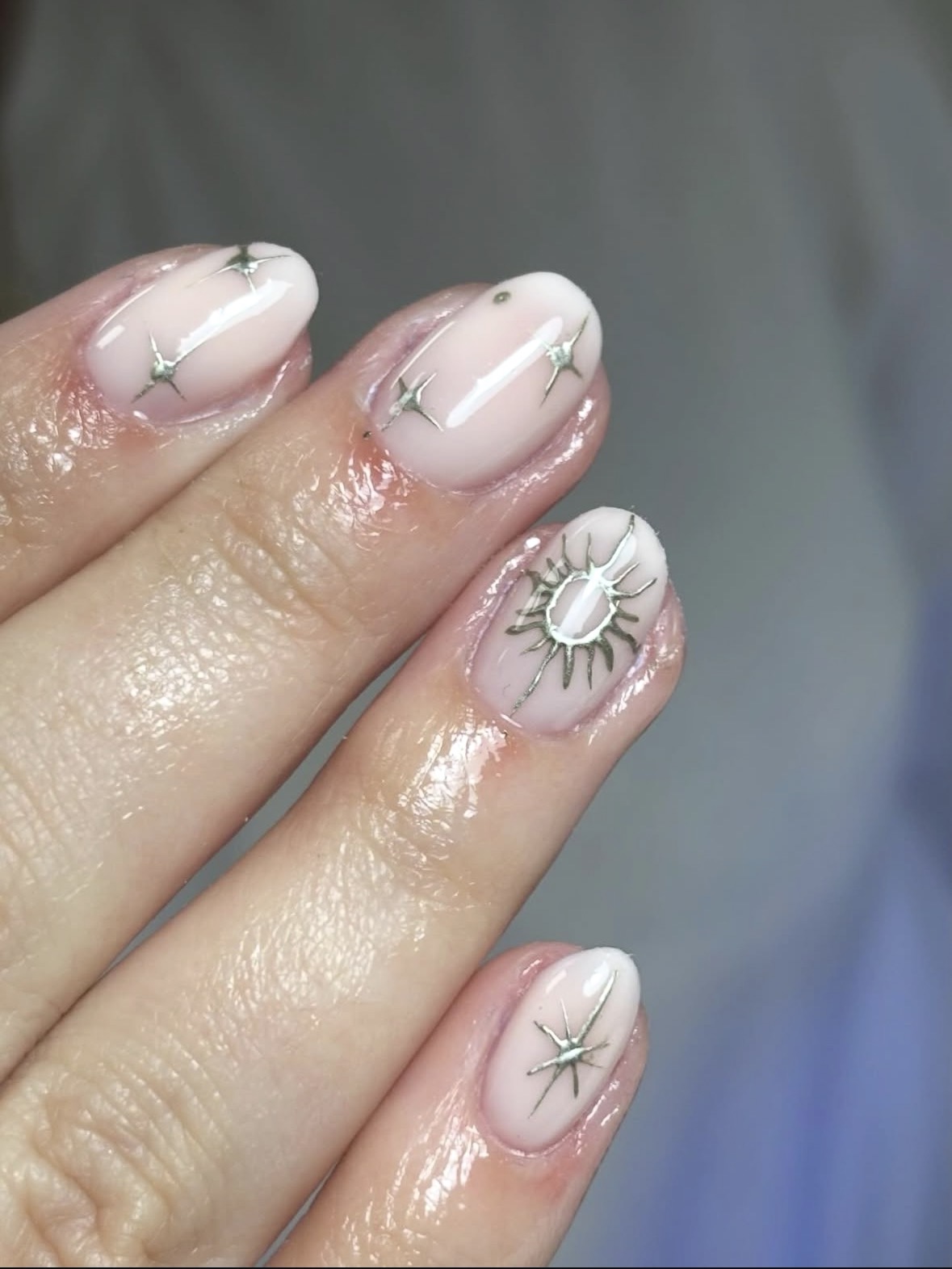 Korte melkwitte nagels met zilveren sterren en een zon in chrome